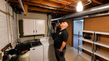 Inspector evaluating basement mechanical and structural components during a detailed home inspection