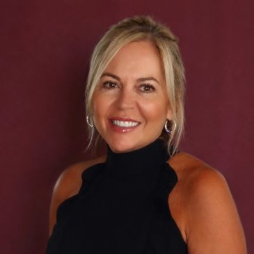 Smiling woman with blonde hair against a maroon background.