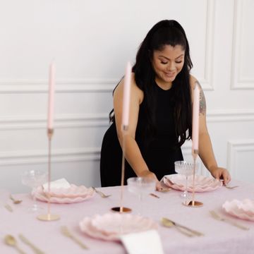 Woman setting an elegant table with pink decor.