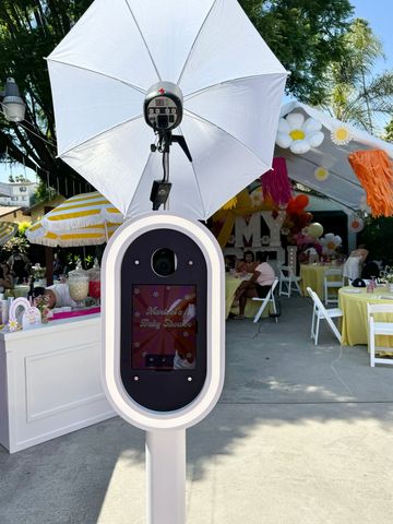 Photo booth setup with umbrella light at outdoor party.