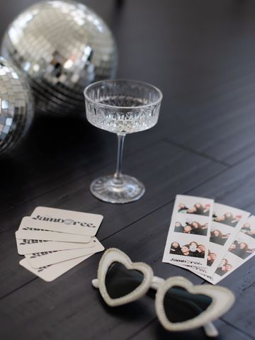 Party items including disco balls, cards, photos, and heart-shaped glasses.