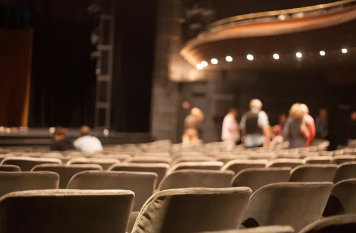 Empty theater seats with blurry figures in the background.