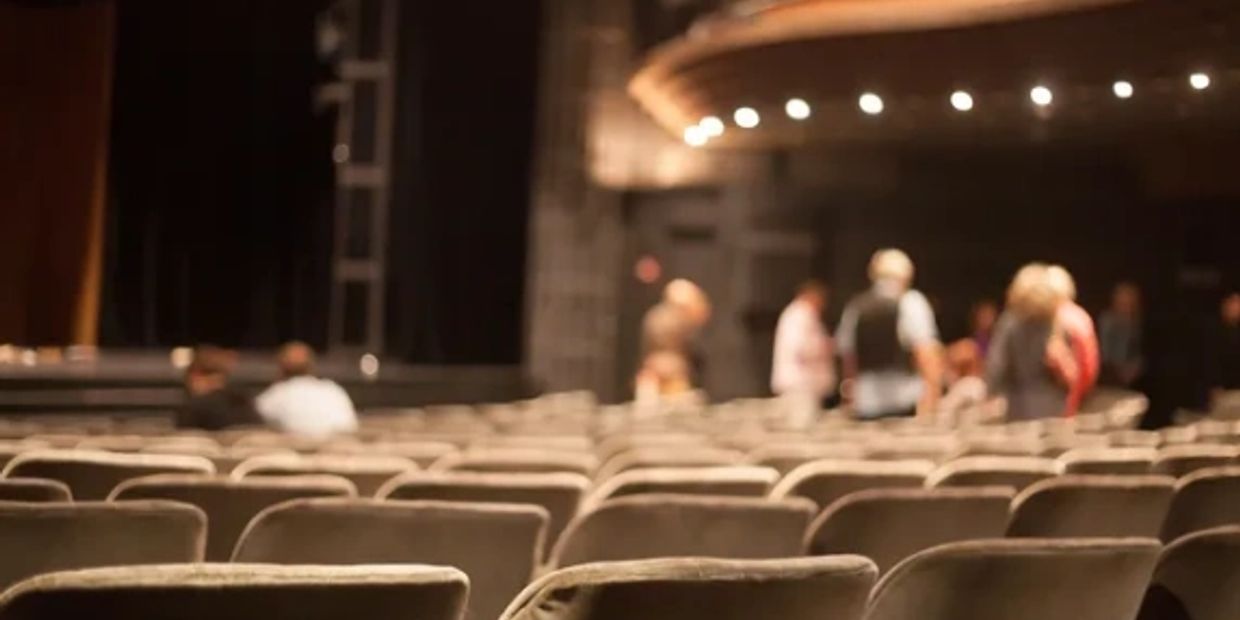 Empty theater seats with a few people in the background.