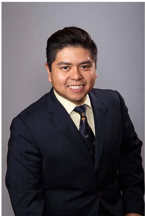 Man in a dark suit smiling at the camera.