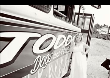 A bride leaning against the original Todd's Dogs Food Truck pictured in black and white