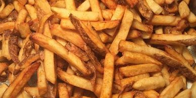 A pan full of fresh cut fries with seasoning salt