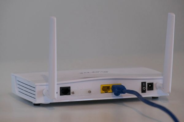 Wireless router with two antennas, and blue network cable patched into yellow data port.