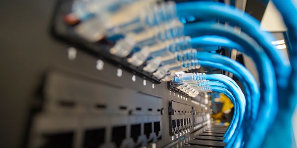 Cat6 patch panel picture from side showing perfectly patched blue cat6 patch cables into ports.