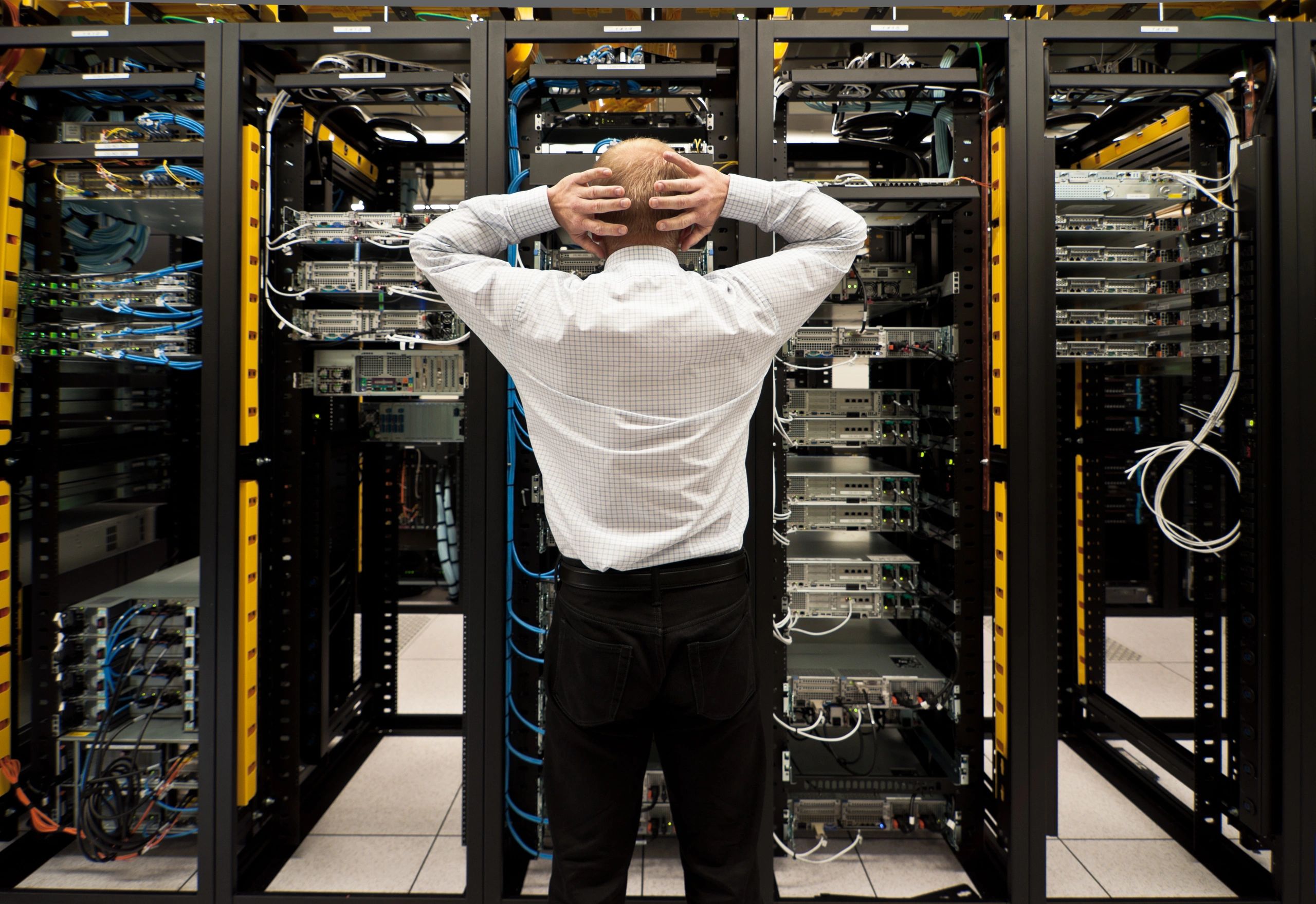 Technician standing satisfied in front of neatly managed and organized data center and data racks.