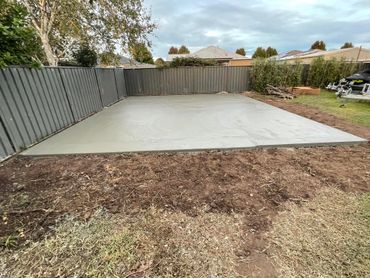 Concrete slab in the corner of the yard with fencing around it