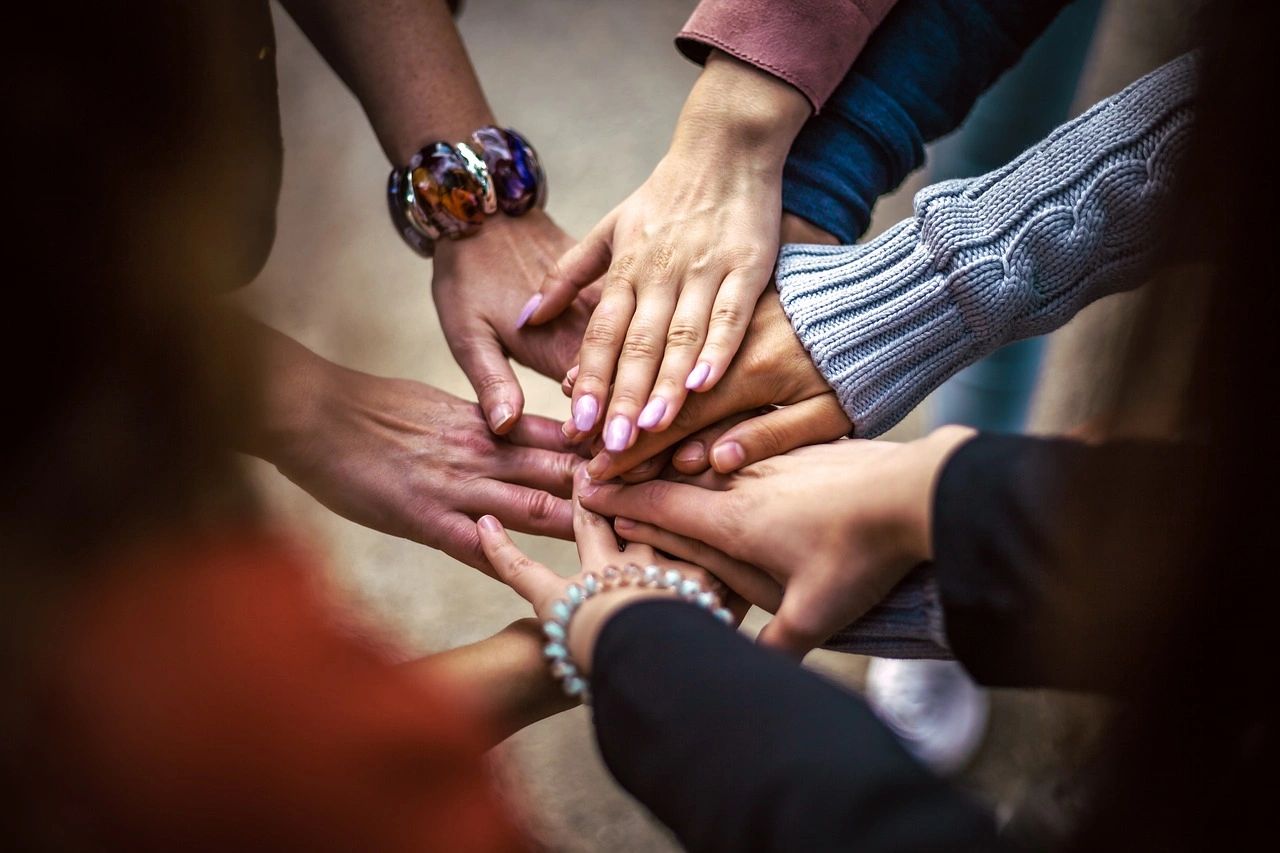 Friends of all races putting hands together in middle of a group