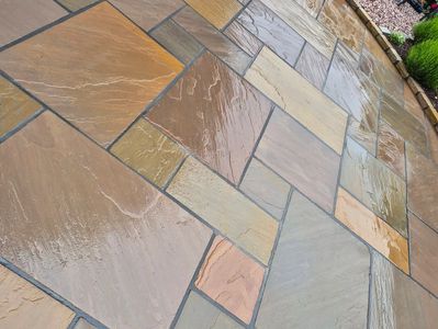 Wet multicolored stone tiles arranged in a patio pattern.