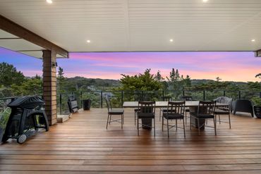 Spacious wooden deck with dining area and scenic sunset view.