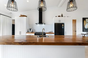 Modern kitchen with wooden countertop and black appliances.
