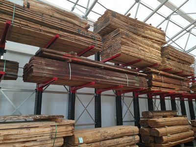 Wofür werden Kragarmregale verwendet? Kragarmregale mit Paketen aus Holz sind zu sehen.