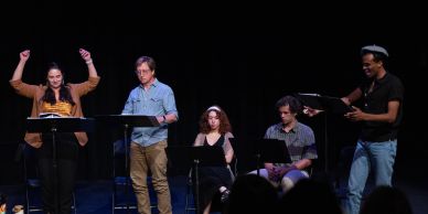 Five actors performing a script reading on stage.