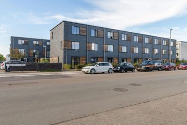 Modern residential buildings with parked cars along the street.