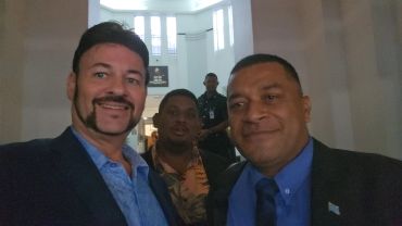Three men posing for a selfie in a formal indoor setting.