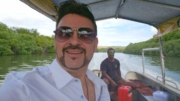 Two men enjoying a boat ride through a scenic river surrounded by greenery.