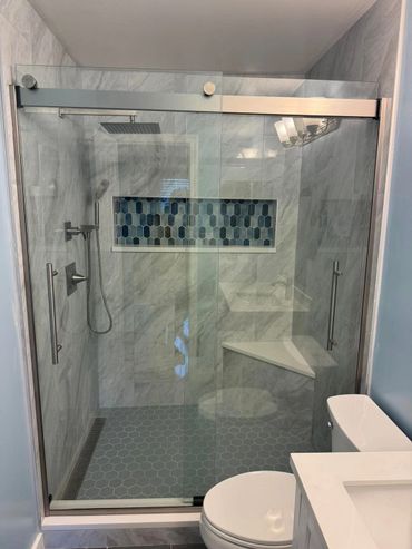 Modern bathroom shower with glass doors and blue hexagonal tile floor.