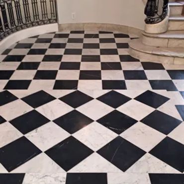 Black and white checkered tile floor with staircase and railing.