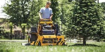 Man mowing lawn with a yellow riding lawn mower.