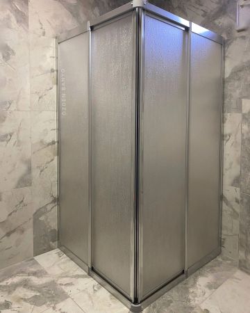 Corner shower enclosure with frosted glass panels in a marble-tiled bathroom.
