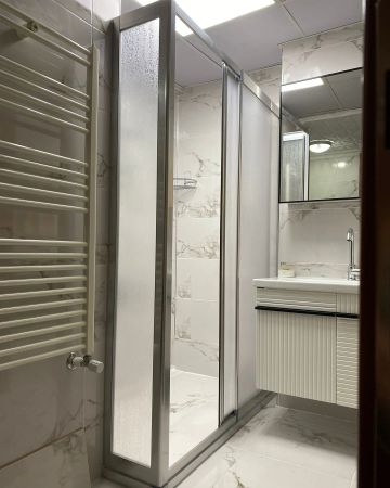 Modern bathroom with frosted glass shower and white marble tiles.