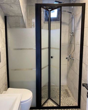 Modern bathroom with a glass shower enclosure and patterned floor tiles.
