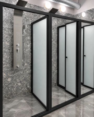 Modern shower stalls with frosted glass and black frames in a sleek bathroom.