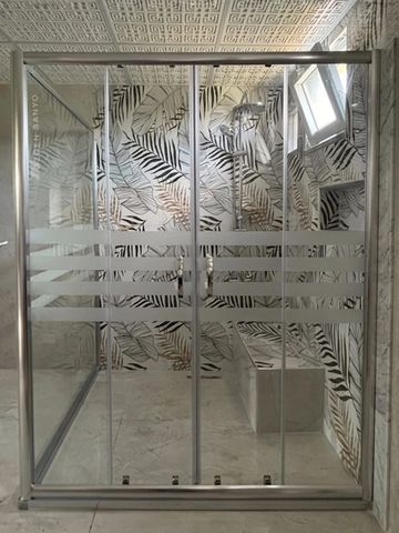 Modern shower with frosted glass and leaf-patterned tiled walls.