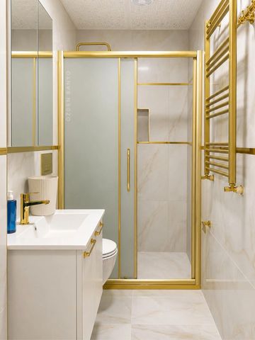 Modern bathroom with gold accents and frosted glass shower door.