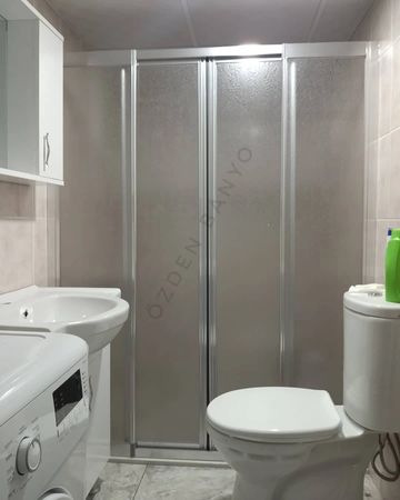 Compact bathroom with shower, toilet, washing machine, and sink.