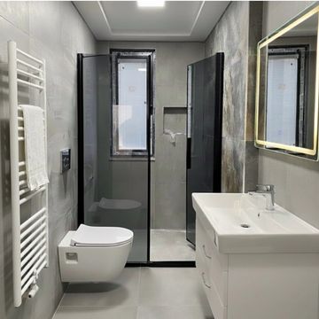 Modern bathroom with glass shower, white sink, and wall-mounted toilet.