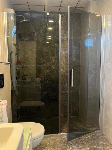 Modern bathroom with glass shower enclosure and marble tiles.