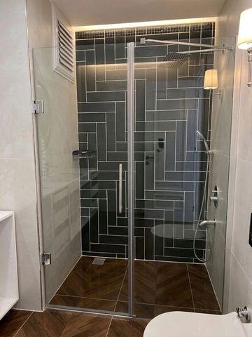 Modern bathroom shower with glass doors and patterned tile walls.