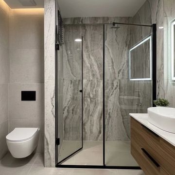 Modern bathroom with glass shower enclosure and floating toilet.