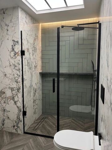 Modern bathroom with glass shower and marble walls.