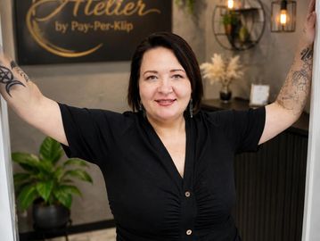 Smiling woman with tattoos posing confidently in a stylish studio.