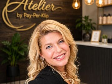 Smiling woman with blonde hair in a stylish salon setting.