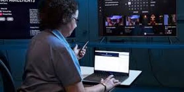 Person using a smartphone and laptop in a tech-focused room.