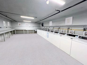 A spacious laundry room with multiple washers and folding tables.