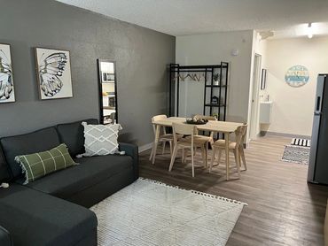 Modern living room with dark sofa, wooden dining table, and butterfly wall art.