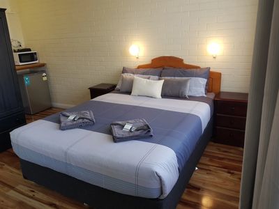 Neatly made bed in a cozy room with wooden floor.