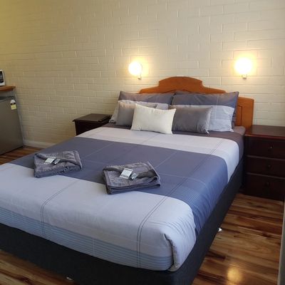 Neatly made bed in a cozy room with wooden floor.