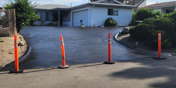 Freshly paved driveway with orange safety cones blocking entry.