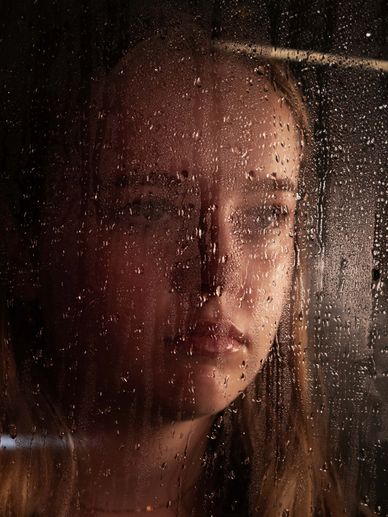 Woman looking through rain-covered glass.