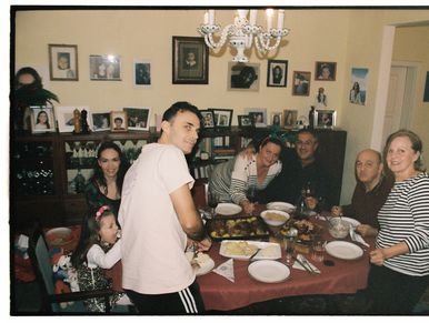 Family gathered around a dinner table smiling.