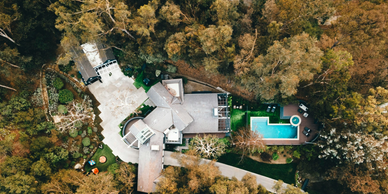 A large house surrounded by trees with a pool in the backyard.