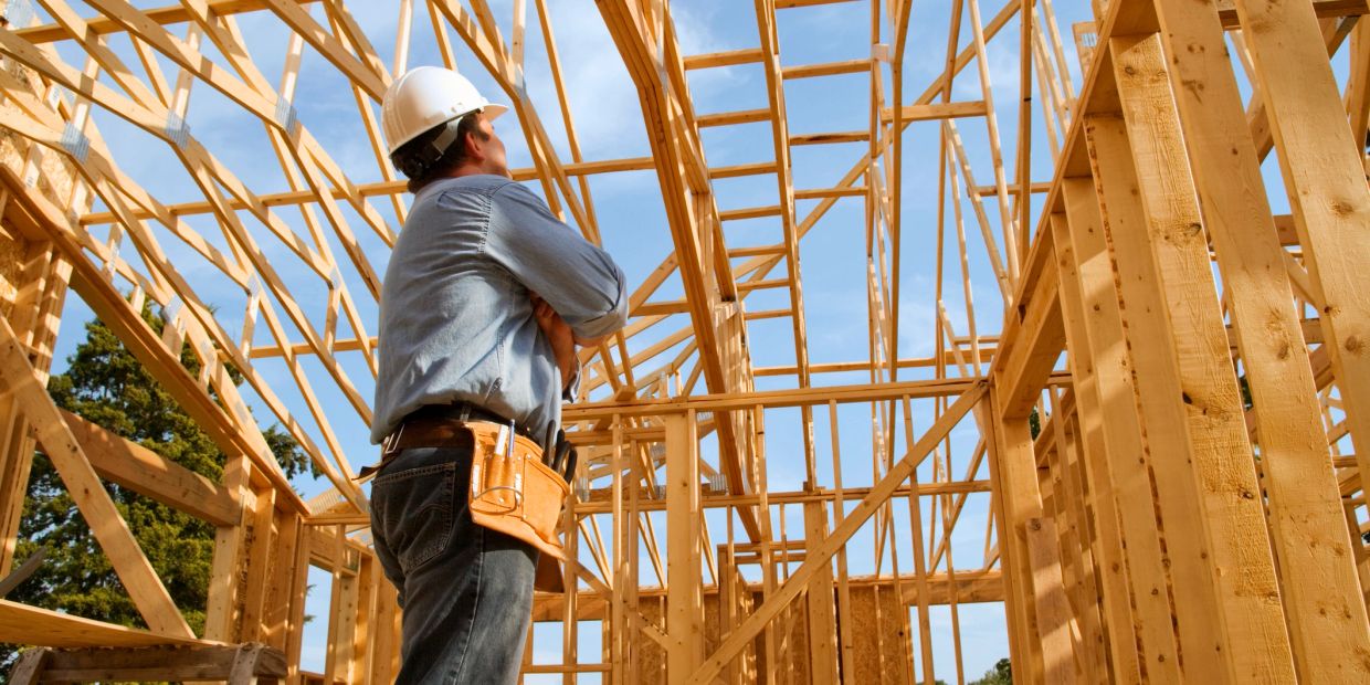 Construction worker inspecting wooden house frame.